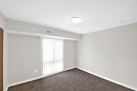 an empty room with white walls and a large window